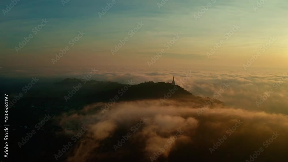 Beautiful golden sunrise sky above fluffy cloudy with antique Buddhism stupa on mountain peak, dramatic light in twilight sky. Aerial view from drone. The panning shot. Beautiful golden sunrise sky above fluffy cloudy with antique Buddhism stupa on mountain peak, dramatic light in twilight sky. Aerial view from drone. The panning shot.