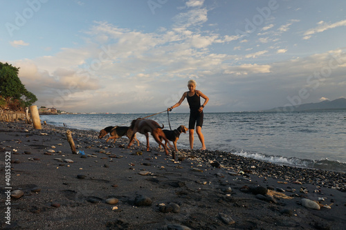 A woman playing with the dogs at Watudodol beach Banyuwangi Indonesia. The sky is amazing and beautiful. photo