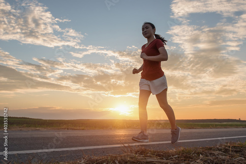 young fitness woman runner running on sunrise road, Exercise concept. © Panya Studio