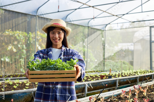 A young female farmer in a greenhouse is delivering organic vegetables to customers.