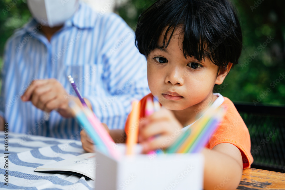 Asian boy practice drawing choosing colour pencil from a box. Asian boy practice drawing choosing colour pencil from a box.