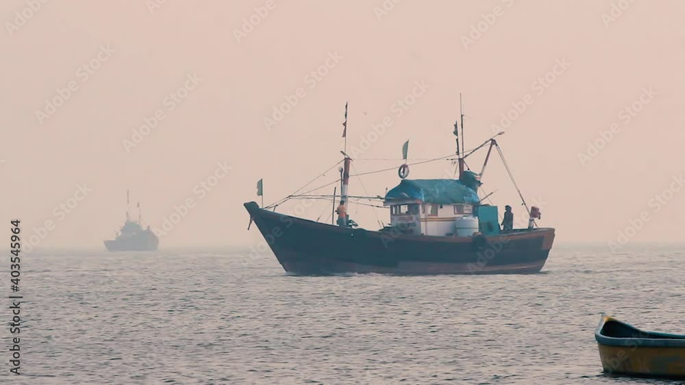 Two Small fisherman boat sailing in middle of the ocean with fisherman preparing to dock during sunset with small calm waves and returning home in foggy weather video background in mov in full HD Two Small fisherman boat sailing in middle of the ocean with fisherman preparing to dock during sunset with small calm waves and returning home in foggy weather video background in mov in full HD
