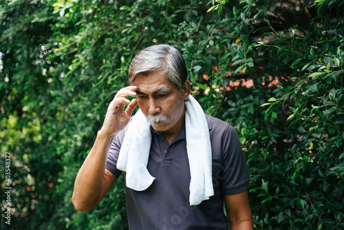 Asian senior elderly man got headache after exercise outdoor at yard.