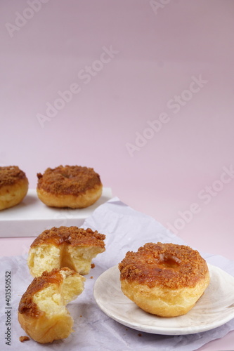 Grainy Donat or Donut or Doughnut with caramel and Lotus biscuit crumbs. Selective focus, pink pastel background