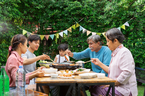 Family enjoy eating BBQ dining at yard to celebrate speacial occasion.