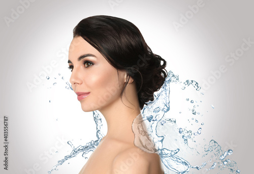 Beautiful young woman and splashing water on light background. Spa portrait