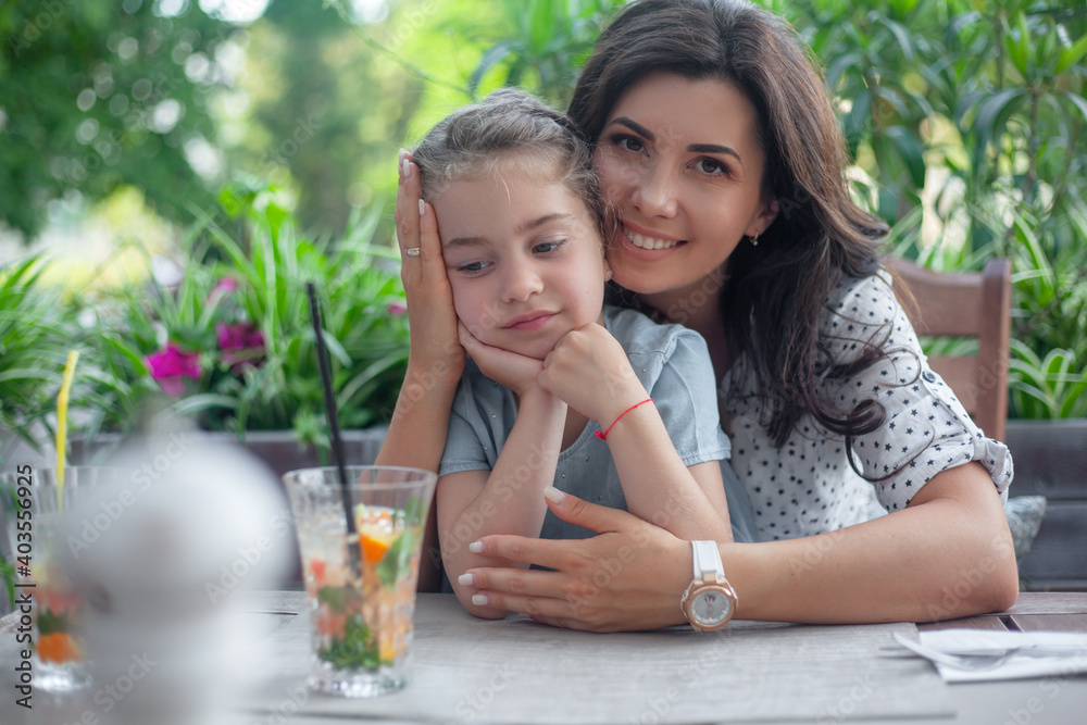 Two people, mother and daughter sit in cafe with cocktails and drink. Happy family spend time together.