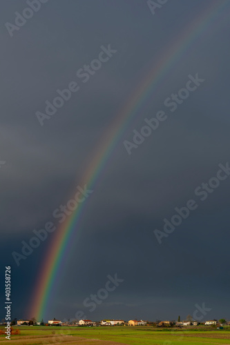 Huge rainbow over the Tuscan countryside against a dark cloudy sky