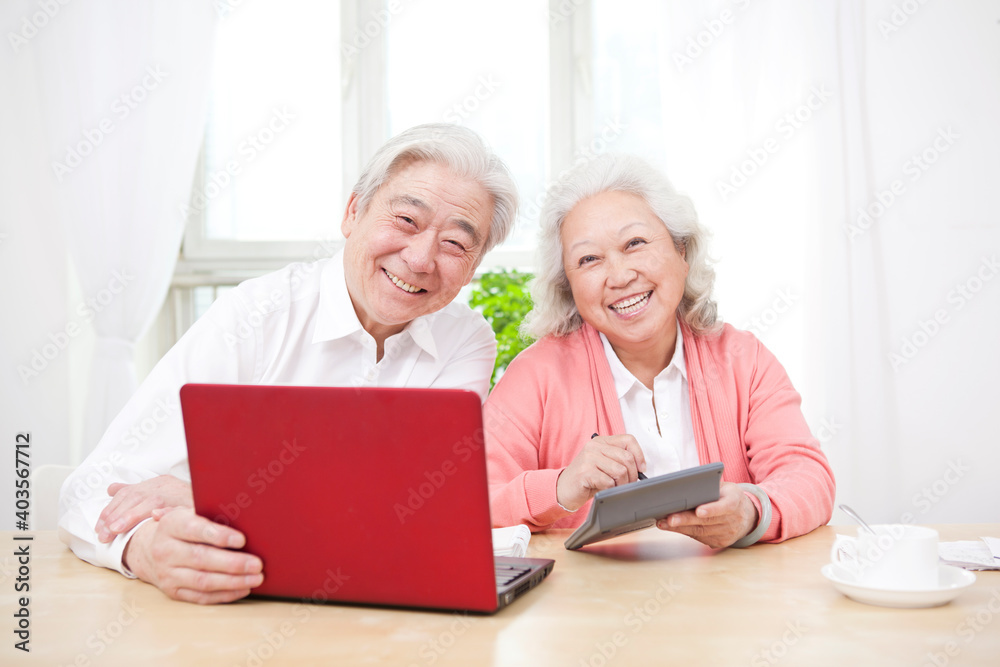 An old couple using laptop and calculator An old couple using laptop and calculator