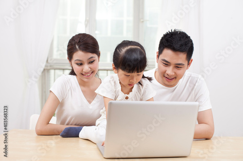 Little girl using laptop with her parents