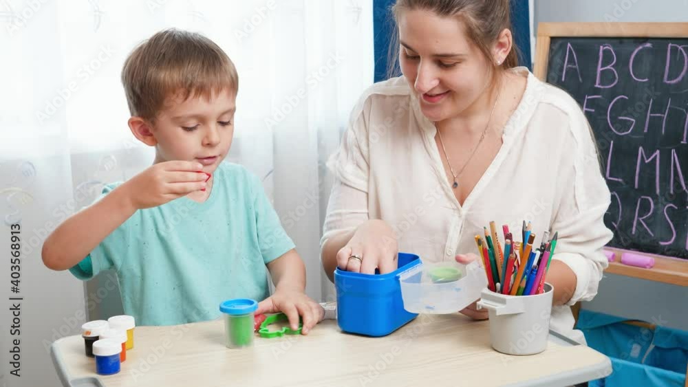 Happy little boy with mother playing with colorful stamps and plasticine. Child education and learning at home. Parent playing and teaching children Happy little boy with mother playing with colorful stamps and plasticine. Child education and learning at home. Parent playing and teaching children