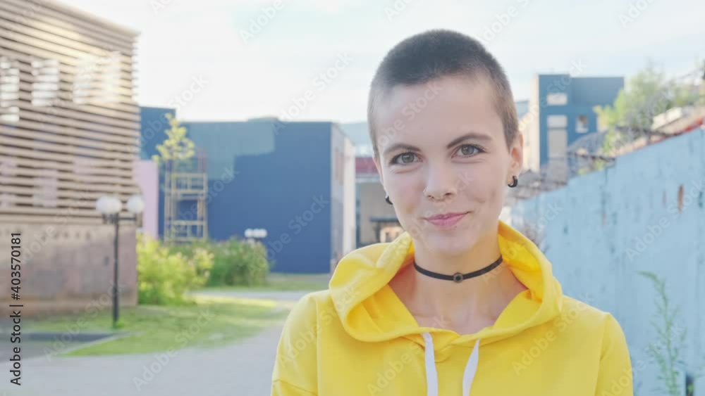 Close up of laughing and smiling young attractive woman with shaved hair in urban outdoor city background. Portrait attractive hipster with nose piercing at summer. Close up of laughing and smiling young attractive woman with shaved hair in urban outdoor city background. Portrait attractive hipster with nose piercing at summer.