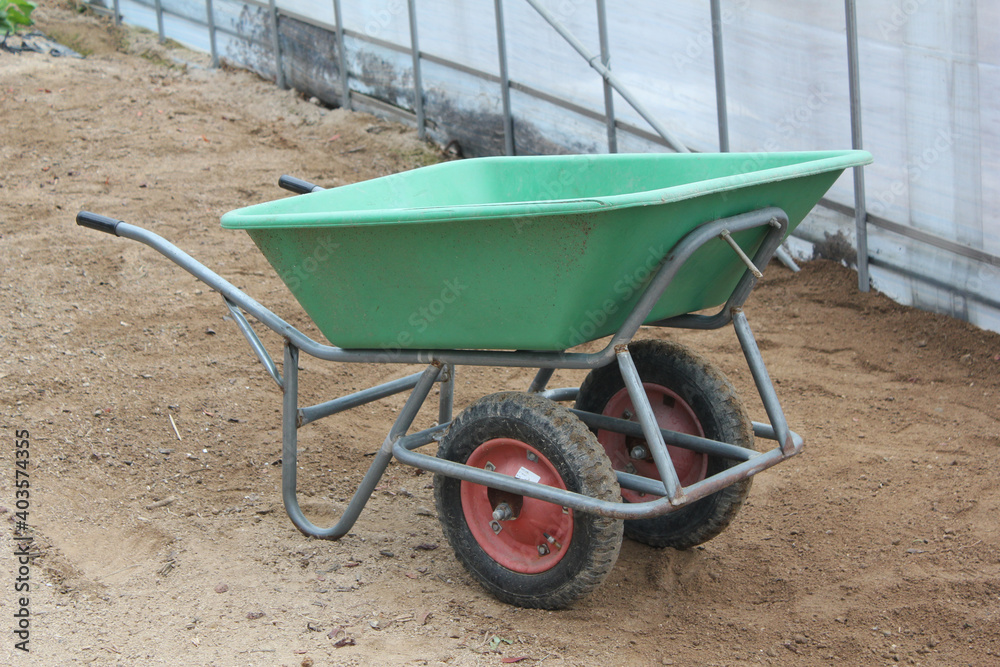 Two-wheeled wheelbarrow ( hand cart ) in a green house Two-wheeled wheelbarrow ( hand cart ) in a green house
