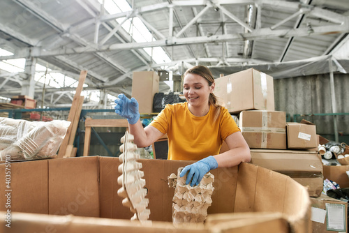 Young caucasian girl throwing egg trays into large box photo