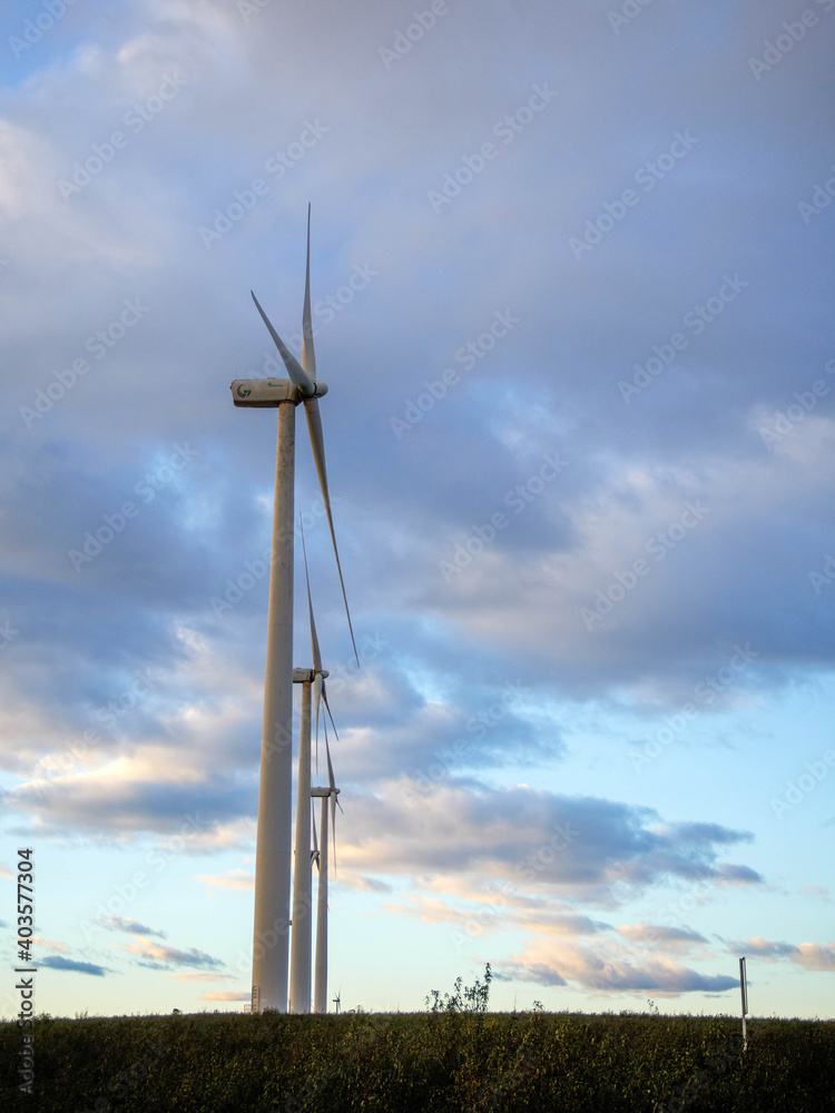 Vertical view of a wind mill with yellow and blue sky.