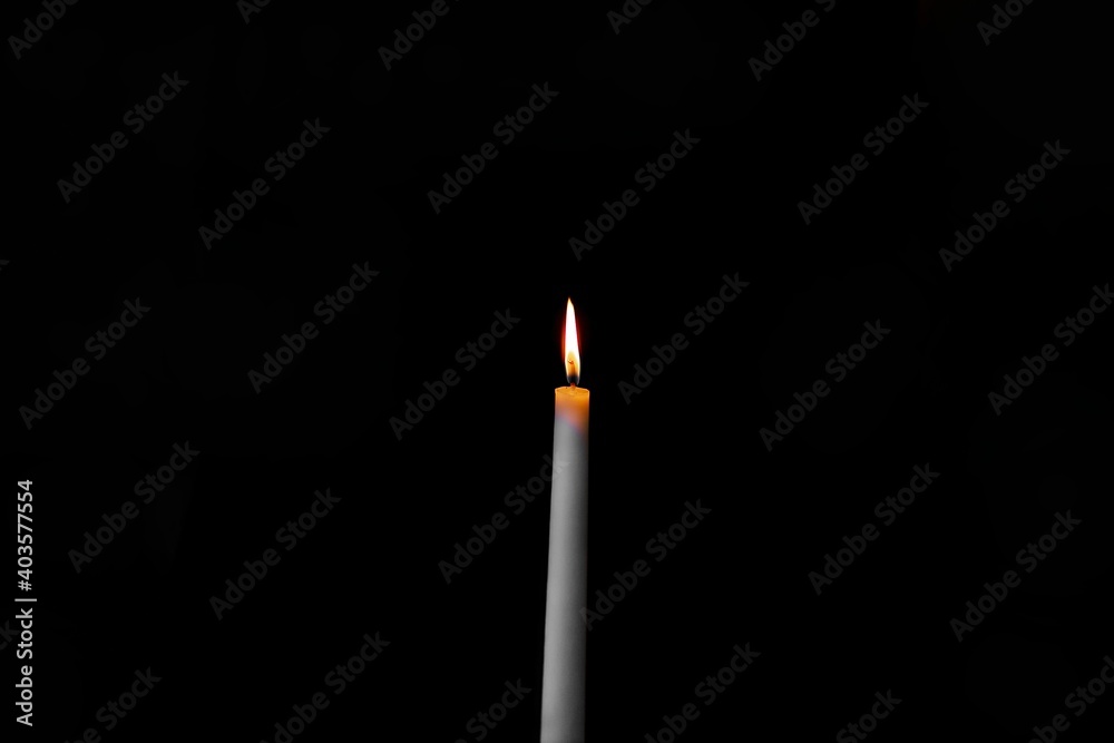 burning candle on a dark background with light from the lights burning candle on a dark background with light from the lights