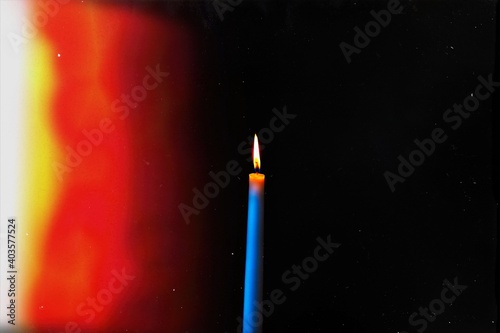 burning candle on a dark background with light from the lights