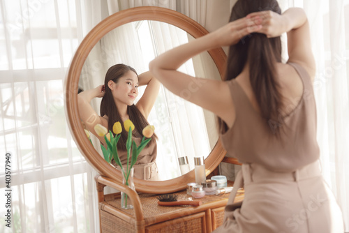 Asian beauty woman tying her hair infront of rounded mirror.