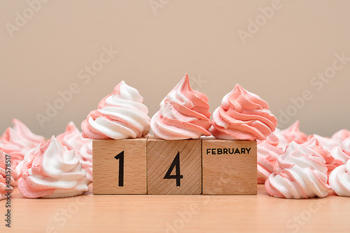 14 February on wooden blocks displayed with pink and white meringues