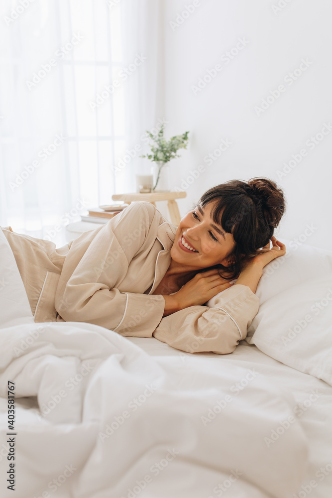 Smiling woman waking up from sleep lying on bed Smiling woman waking up from sleep lying on bed