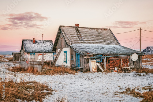 Authentic northern village, old ethnic fishing houses, firewood stacked in piles.