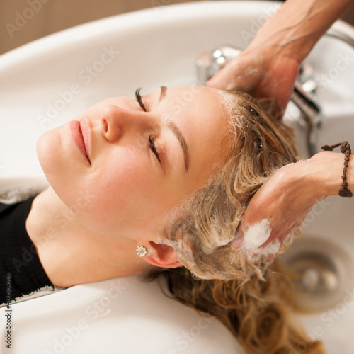 Hair stylist at work - hairdresser washing hair to the customer before doing hairstyle in a professional salon