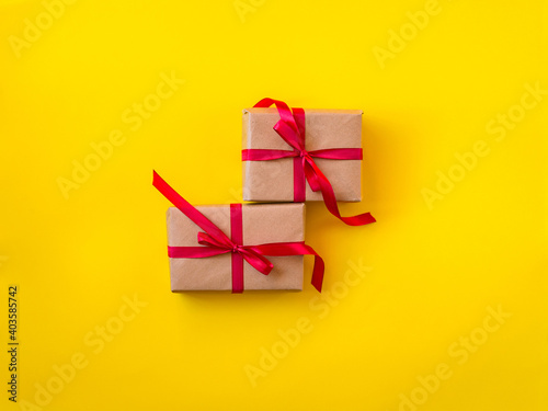 Gifts decorated with red ribbon, yellow background, copy space. Two present boxes, top view. Valentine or love, spring holidays, Christmas and birthday concept.
