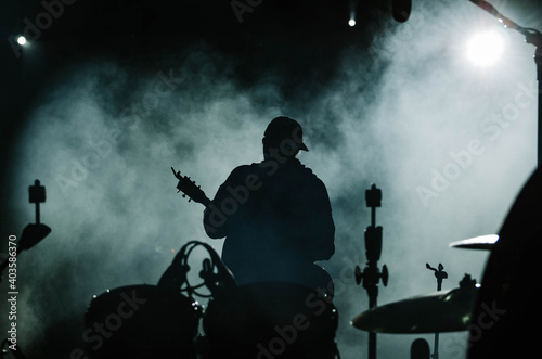Guitarist stands with his back at a concert, a lot of smoke on a dark background