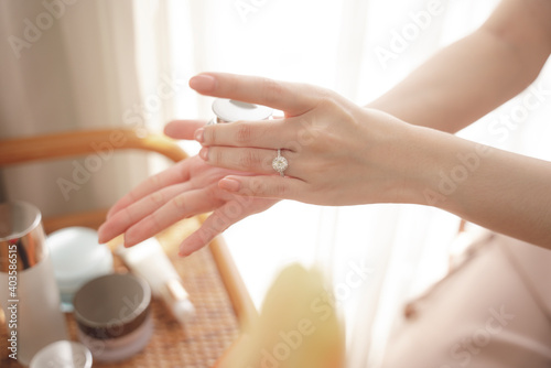 Hand of woman using cream lotion jar at cosmetic desk.