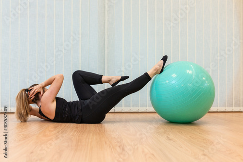 girl pilates trainer does criss cross fitball posture in fitness center