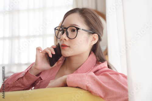 Young asian beauty woman wear eyeglasses talking on the phone at home.