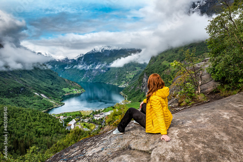 Woman in yellow sitting over Geiranger fjord photo
