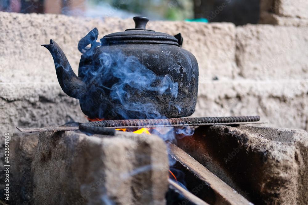 A charred kettle is heating water in the stove