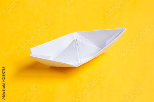 White paper ship isolated on yellow background. Origami boat.