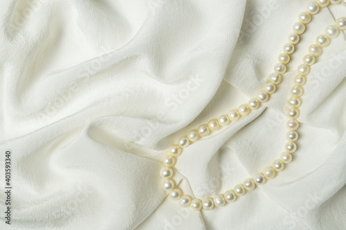Beautiful white silk fabric with pearl beads. Elegant and romantic background.