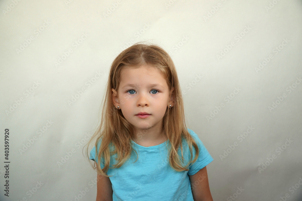 Naklejka premium Cute little girl shows emotions on a white background in a T-shirt. Simple beauty. High quality photo