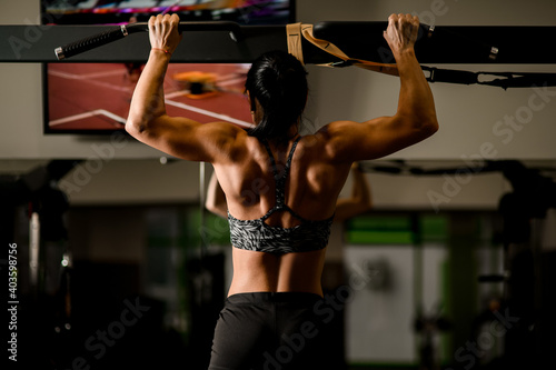 Close-up view of muscular woman doing pull ups in gym. Bodybuilding concept.