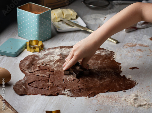 Children's hands carve cookies from chocolate dough photo