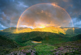 Dramatic stunning rainbow at first light during sunrise over Blea Tarn in the Lake District, with heather in bloom