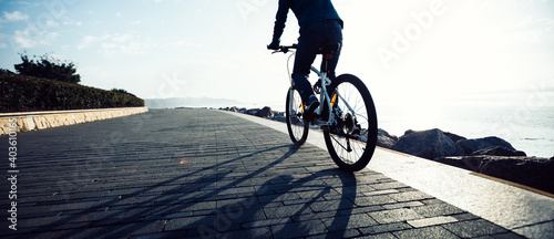 Fotografia Cyclist riding bike in the sunrise coast path