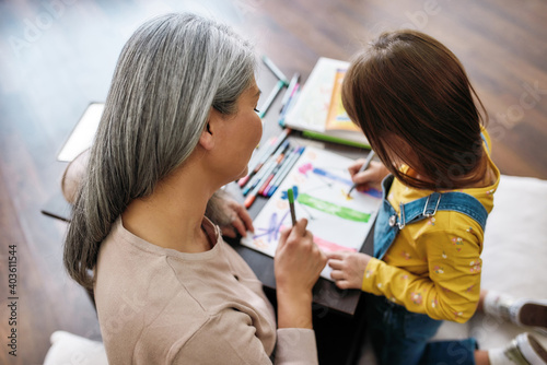 Grandmother sitting beside granddaughter during drawing