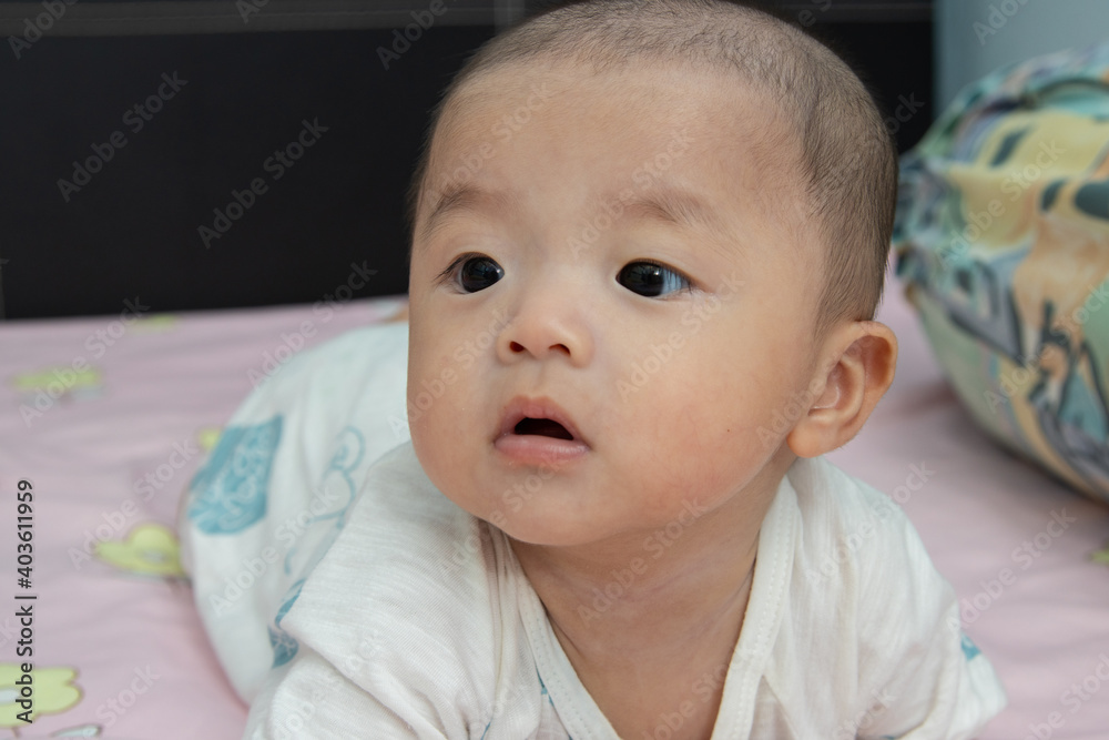 Closeup Portrait Adorable and happy Chinese baby boy on tummy time on bed. Newborn child relaxing in bed Closeup Portrait Adorable and happy Chinese baby boy on tummy time on bed. Newborn child relaxing in bed