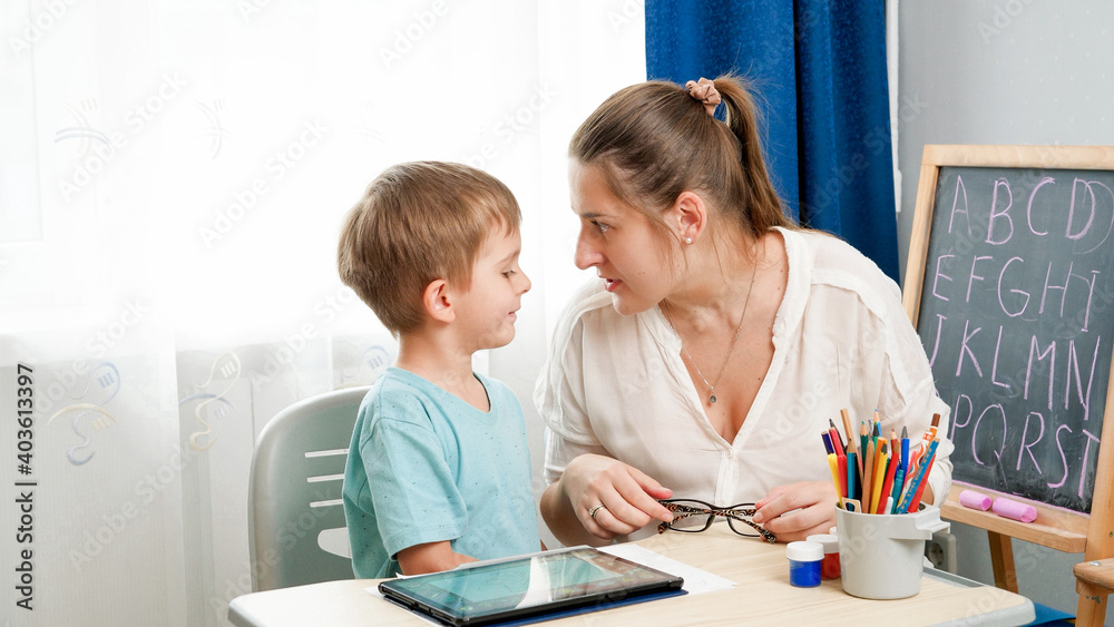 ANgry mother looking in face of her little son being silly while doinghomework at remote home school lesson ANgry mother looking in face of her little son being silly while doinghomework at remote home school lesson