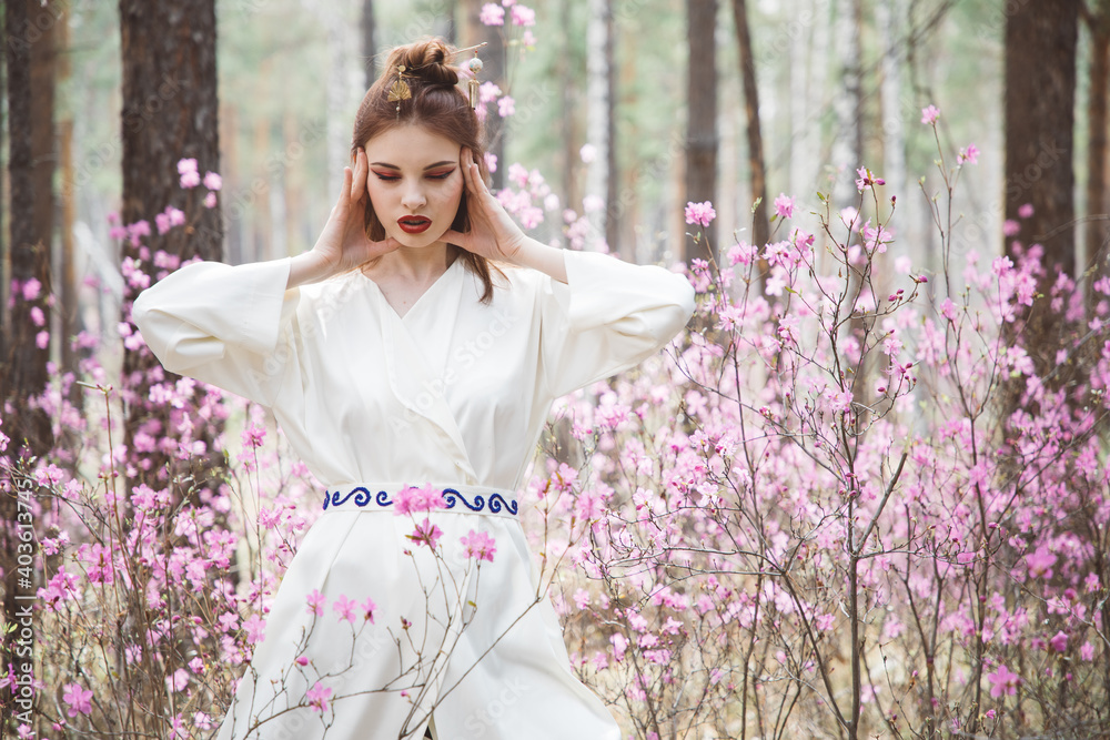 Japanese-style girl in a flowering forest among pink flowers in spring Japanese-style girl in a flowering forest among pink flowers in spring