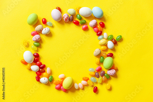 Happy Easter concept. Preparation for holiday. Easter candy chocolate eggs and jellybean sweets isolated on trendy yellow background. Simple minimalism flat lay top view copy space.