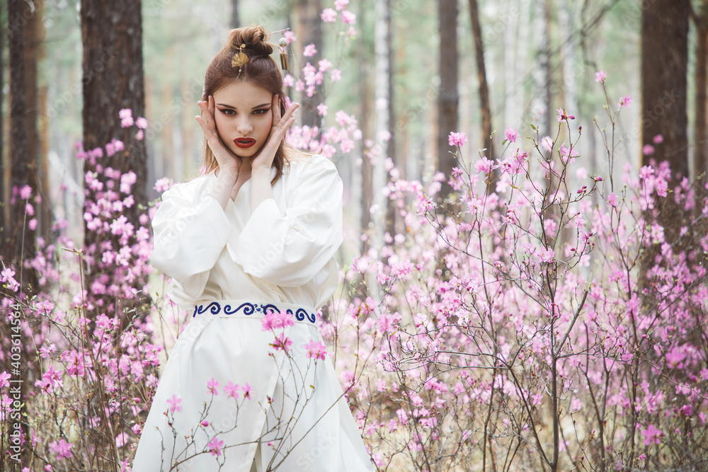 Japanese-style girl in a flowering forest among pink flowers in spring Japanese-style girl in a flowering forest among pink flowers in spring
