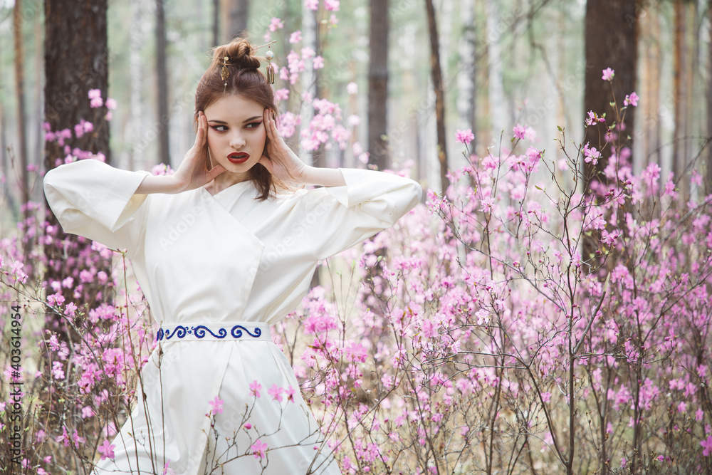 Japanese-style girl in a flowering forest among pink flowers in spring Japanese-style girl in a flowering forest among pink flowers in spring