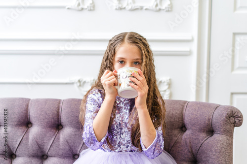 Beautiful little girl holding Christmas mug in bright interior