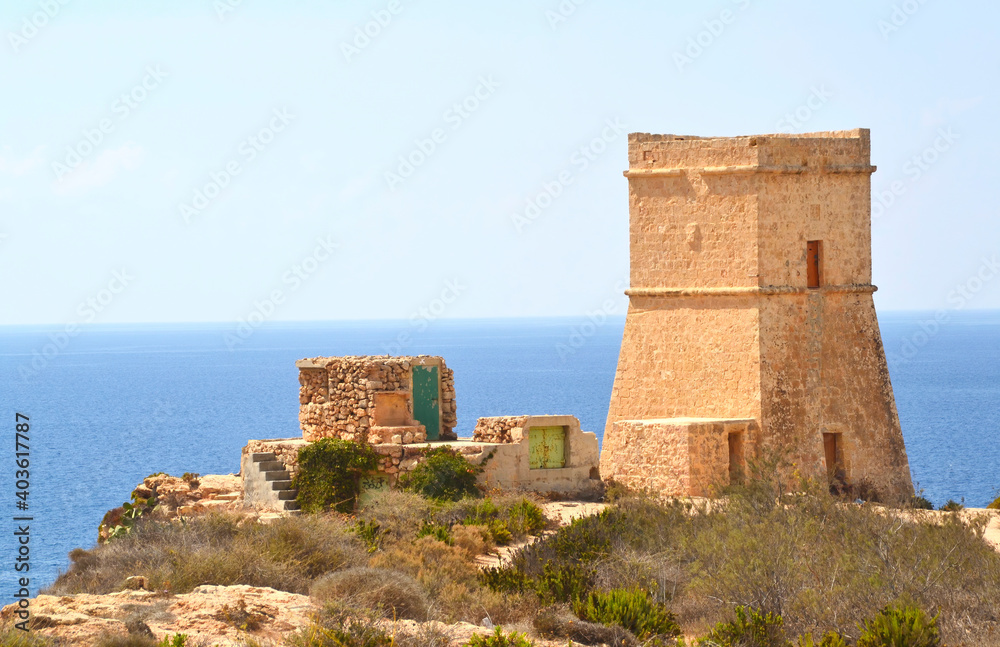 Old tower on the coast of the island of Malta, the mediterranean sea on background
