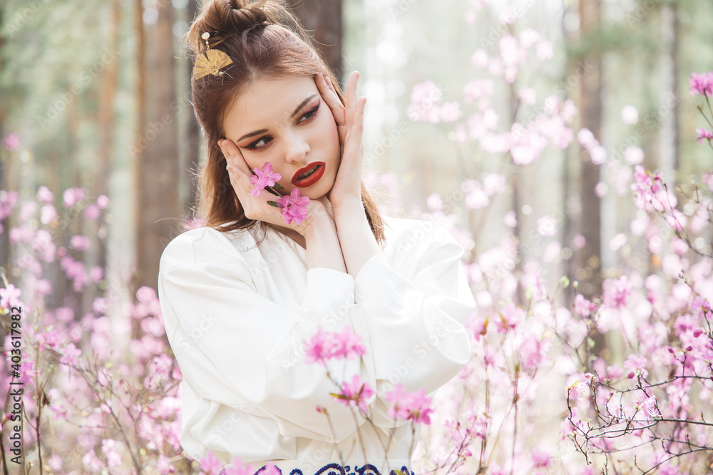 Japanese-style girl in a flowering forest among pink flowers in spring Japanese-style girl in a flowering forest among pink flowers in spring